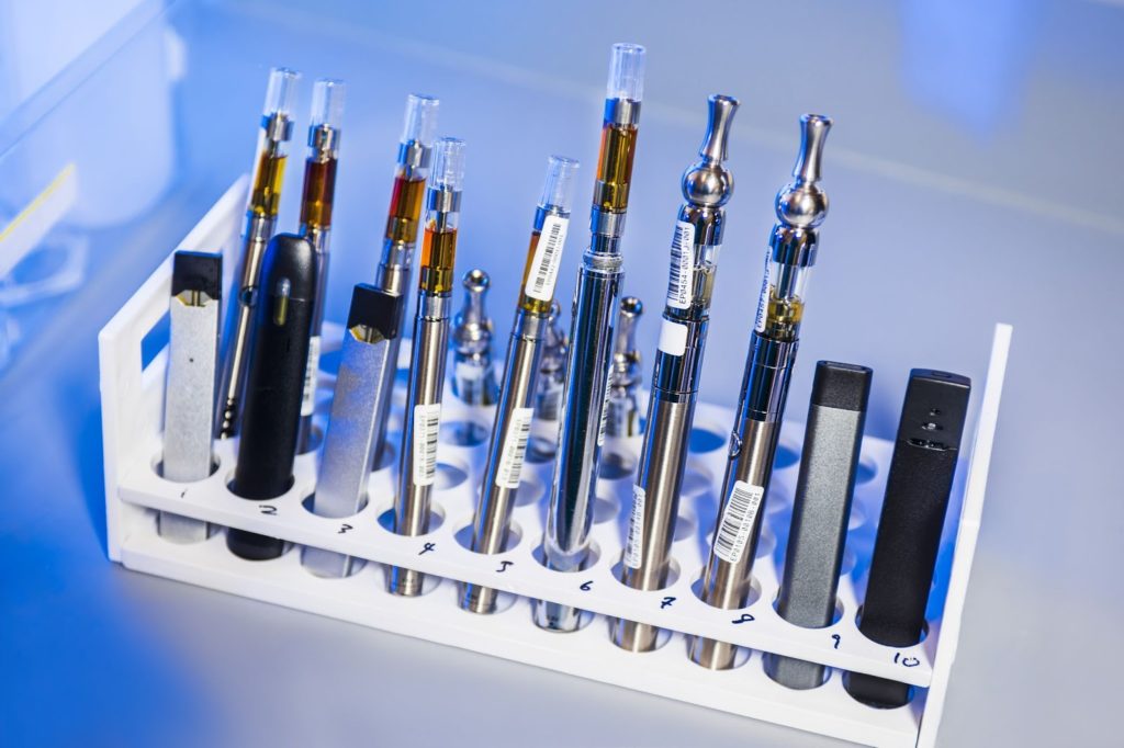 Many types of tobacco vapes in a display rack in a retail store for purchase.