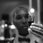 man holding a shot of rum in his hand.