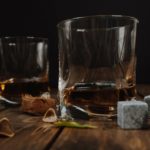 2 clear glasses with scotch and whiskey cubes