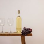 Two Clear Wine Glasses Beside Clear Glass Bottle on Brown Wooden Table
