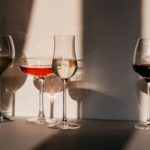Different sorts of wine in various glasses on table in sunlight