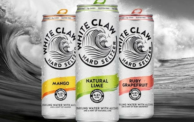 3 cans of white claw with a wave in the background